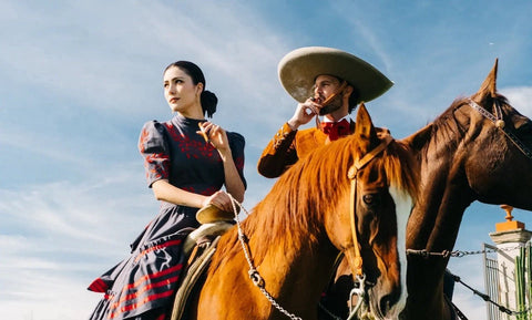Couple on horseback in traditional Mexican dress smoking cigars at a hacienda, marking Casa 1910 Teniente Angela Toro as Cigar of the Month - Toro Puro