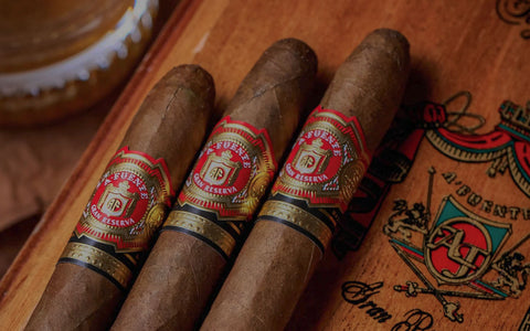 Three cigars with brand labels on a wooden surface