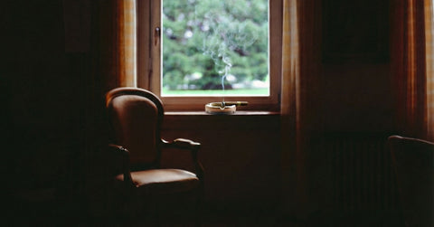 cigar on an ashtray next to a window and a chair toro puro