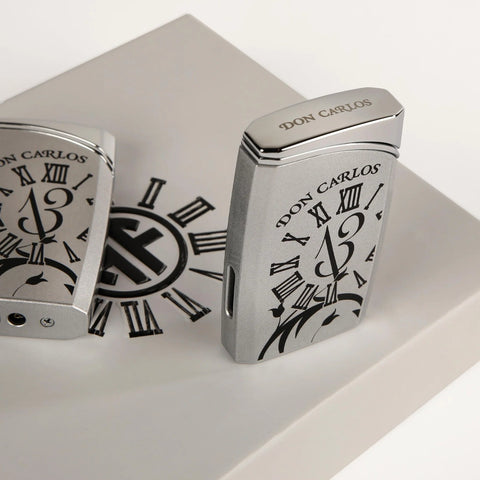 Two silver lighters with 'Don Carlos' branding on a white surface.
