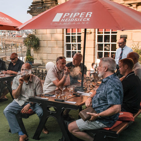 Guests enjoying cigars and drinks at a Toro Puro cigar tasting event on an outdoor terrace in South Wales