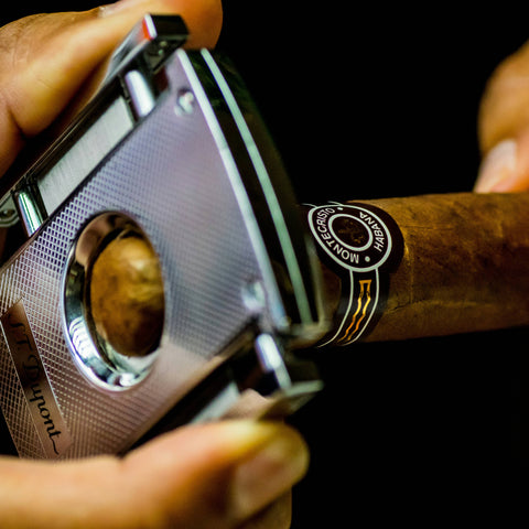 Cigar cutter being used on a Moncayo cigar with a dark background