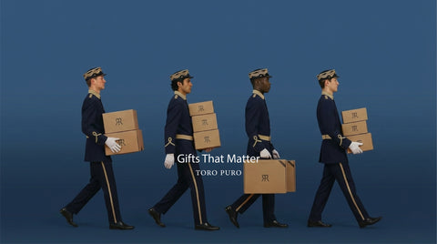 Four uniformed personnel carrying boxes with 'Gifts That Matter' and 'TORO PURO' text on a blue background.