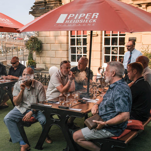 Guests enjoying cigars and drinks at a Toro Puro cigar tasting event on an outdoor terrace in South Wales